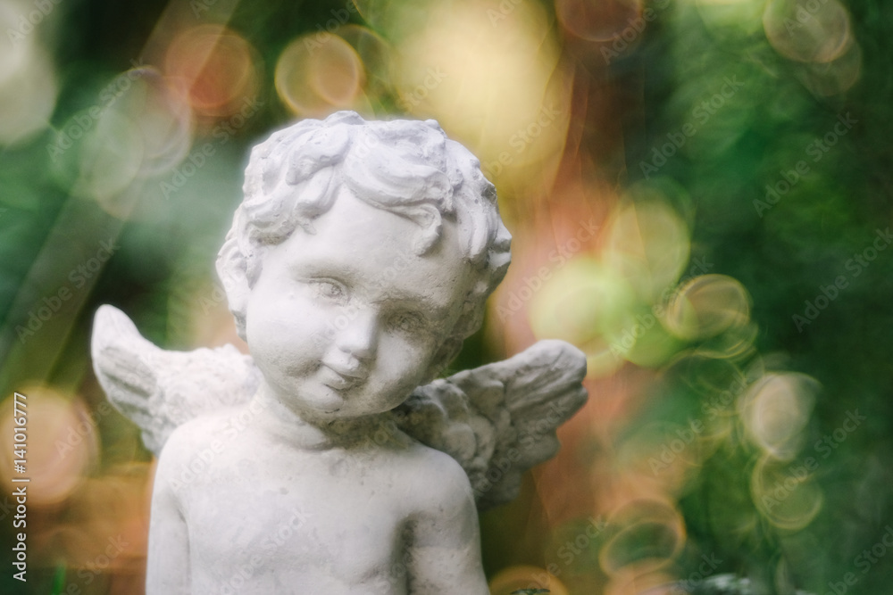 Cupid sculpture in garden the background is blurred bokeh from tree, background for Valentine's day. color toned.