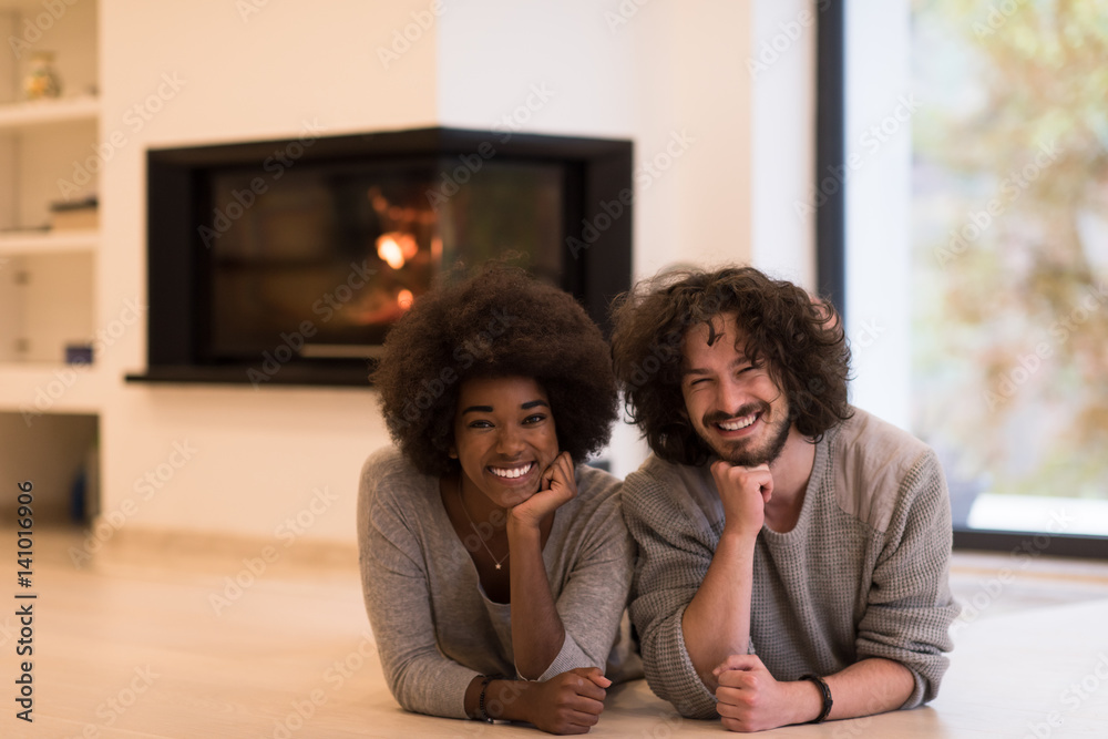 multiethnic couple lying on the floor in front of fireplace multiethnic couple lying on the floor in front of fireplace