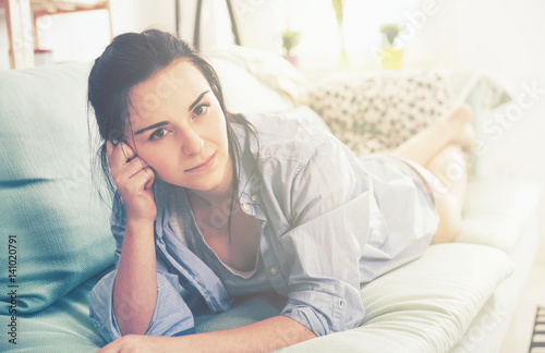 Young relaxed woman while lying on comfortable sofa home interior