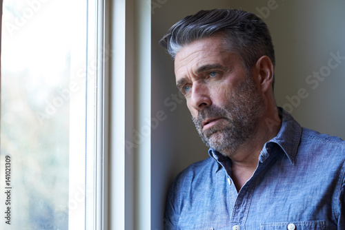 Quadro su tela Mature Man Suffering From Depression Looking Out Of Window