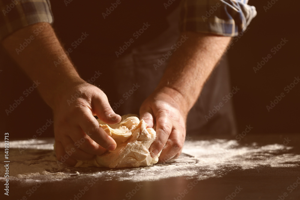 Fototapeta premium Man kneading dough in kitchen, closeup