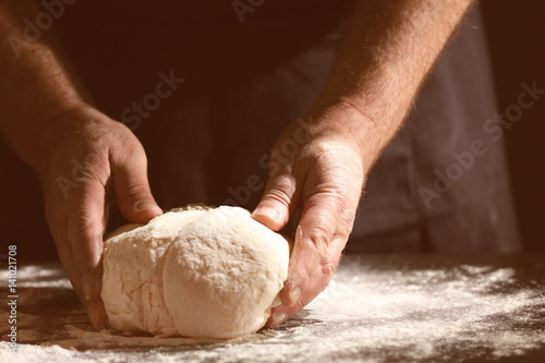 Man kneading dough in kitchen, closeup