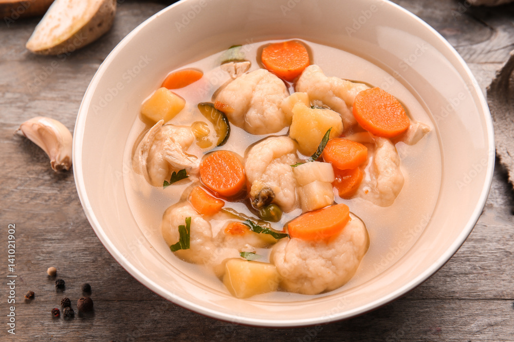 Bowl of delicious chicken and dumplings on wooden dining table Bowl of delicious chicken and dumplings on wooden dining table