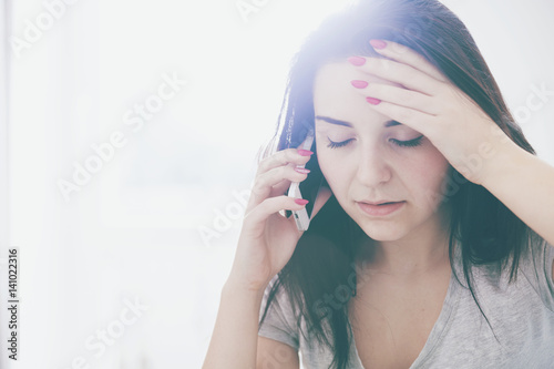 Картината върху платно Unhappy worried woman talking on phone at home