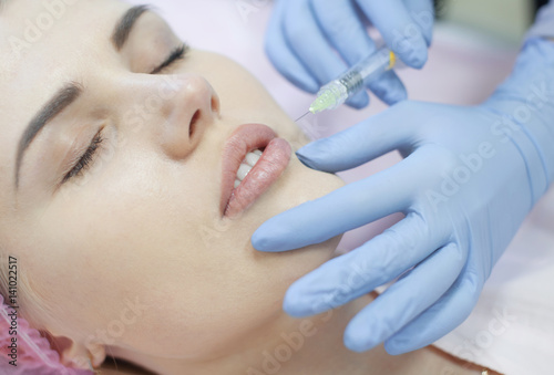 Hands of cosmetologist making injection in face, lips. Young woman gets beauty facial injections in salon. Face aging, rejuvenation and hydration procedures. Aesthetic cosmetology. Close up.