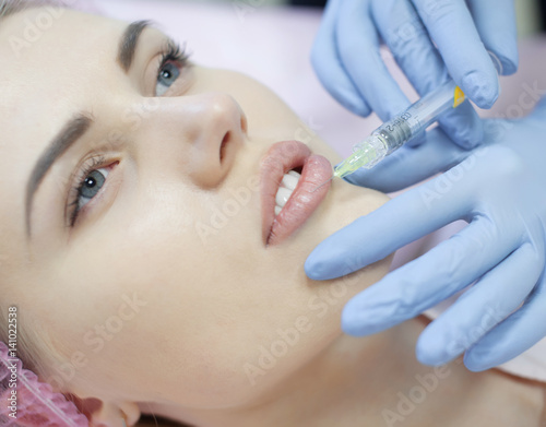 Hands of cosmetologist making injection in face, lips. Young woman gets beauty facial injections in salon. Face aging, rejuvenation and hydration procedures. Aesthetic cosmetology. Close up. © lashkhidzetim