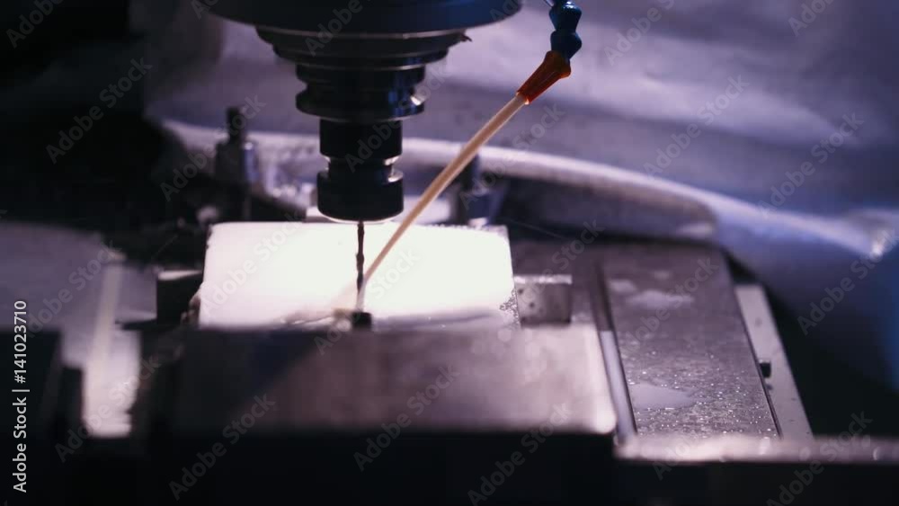 Milling CNC machine tool cuts out metal parts, cooling with liquid, drill. Automatic production process. Сlose-up. 4k footage. 
