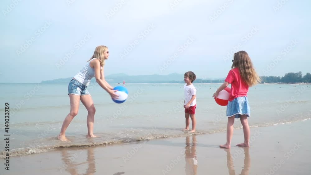 kinder und mutter spielen mit buntem wasserball auf einem schönen sandstrand in thailand kinder und mutter spielen mit buntem wasserball auf einem schönen sandstrand in thailand