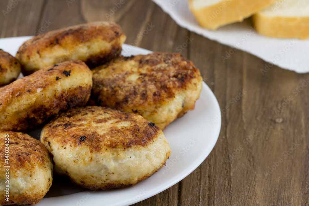 Hot meat cutlet and fresh bread on a wooden background. Close up