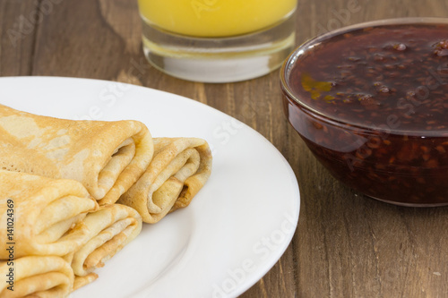 Pancakes or Russian Blintzes with jam on a wooden background. Close up