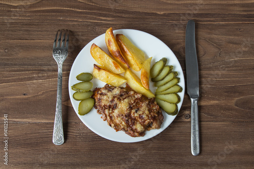 Grilled meat with potato and cucumbers on a wooden background photo