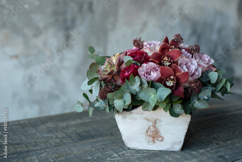 A bouquet of roses in a wooden vase is on the table. Flower arrangement in a wooden flowerpot photo