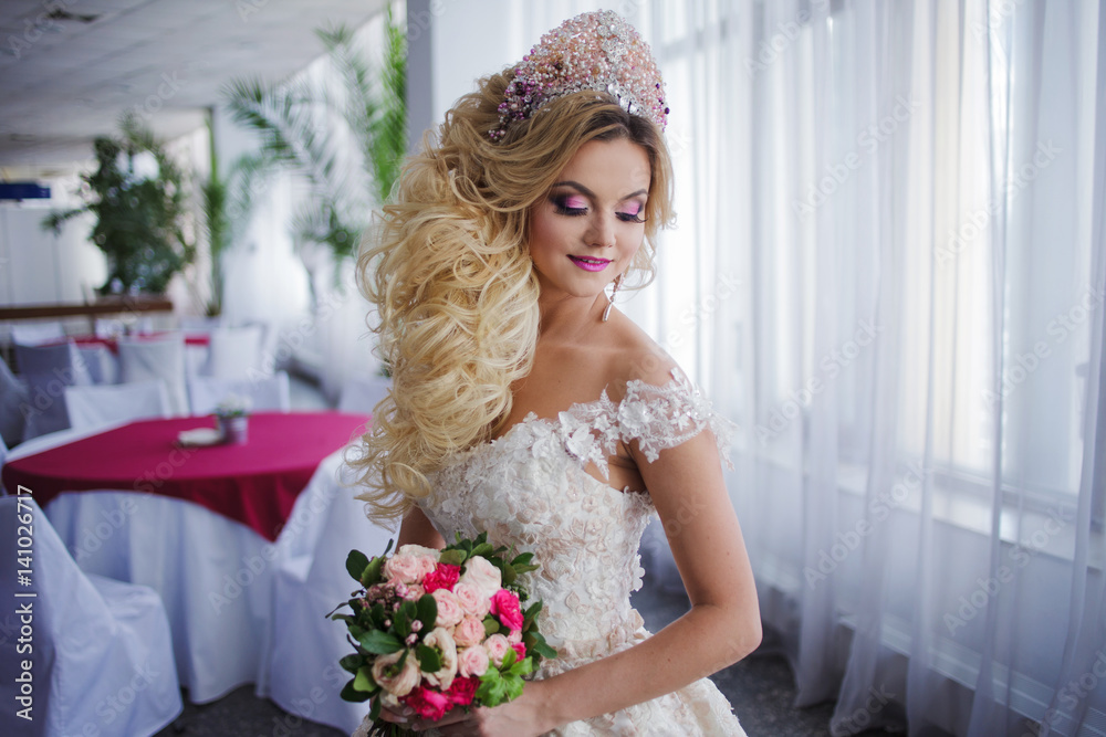 Young fashion bride with perfect skin and make up, curly hair, flowers and tiara on the head, indoors Young fashion bride with perfect skin and make up, curly hair, flowers and tiara on the head, indoors