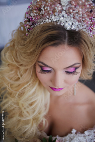 Young fashion bride with perfect skin and make up, curly hair, flowers and tiara on the head