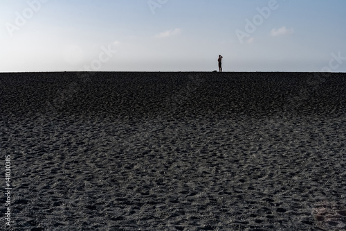 one person standing on deserted beach looing at distant horizon