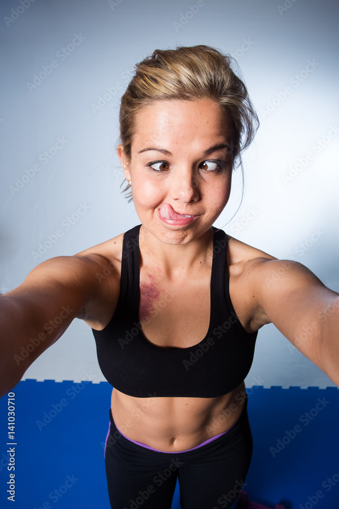 Beautiful female fitness model resting after a hard training session and taking a selfie for social media Beautiful female fitness model resting after a hard training session and taking a selfie for social media