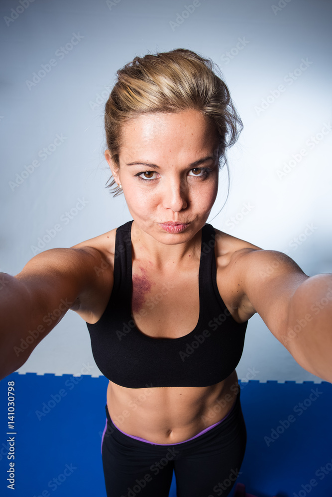 Beautiful female fitness model resting after a hard training session and taking a selfie for social media Beautiful female fitness model resting after a hard training session and taking a selfie for social media