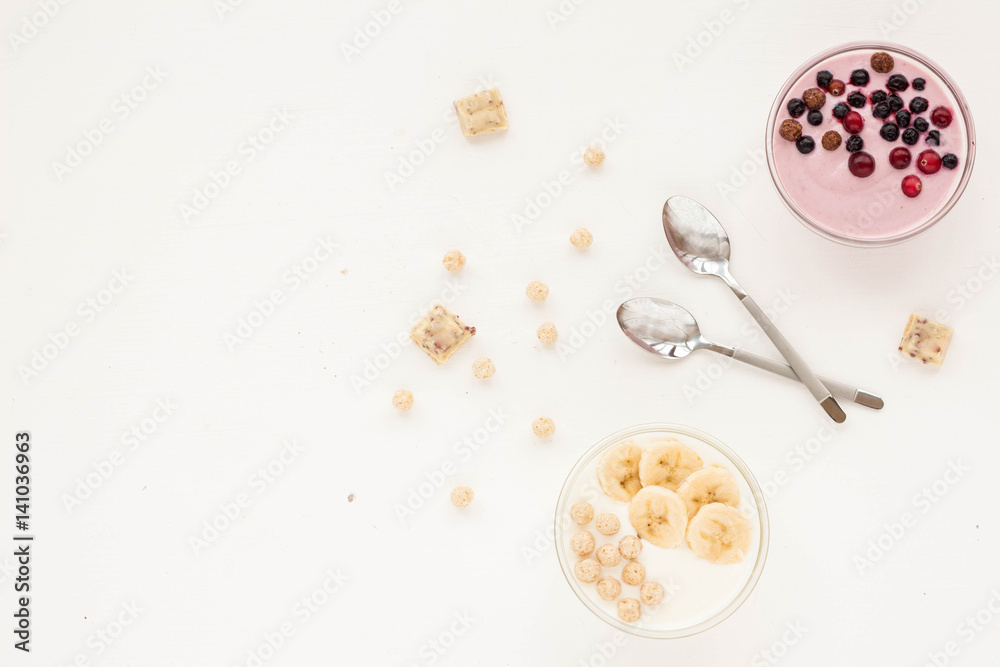 Healthy breakfast with yogurt, muesli, banana and berries on white background. Flat lay Healthy breakfast with yogurt, muesli, banana and berries on white background. Flat lay