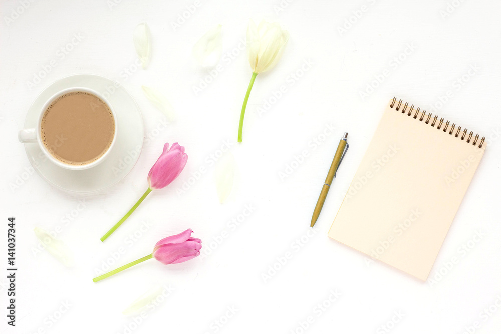 Flowers composition. Woman's workspace wiht notebook, cup of coffee white and lilac tulip, pen on white background. Flat lay, top view Flowers composition. Woman's workspace wiht notebook, cup of coffee white and lilac tulip, pen on white background. Flat lay, top view