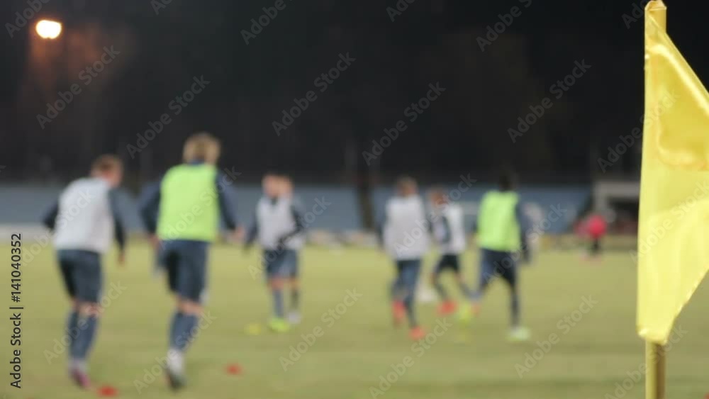 Blurred football (soccer) players warm up during training session beside corner flag Blurred football (soccer) players warm up during training session beside corner flag