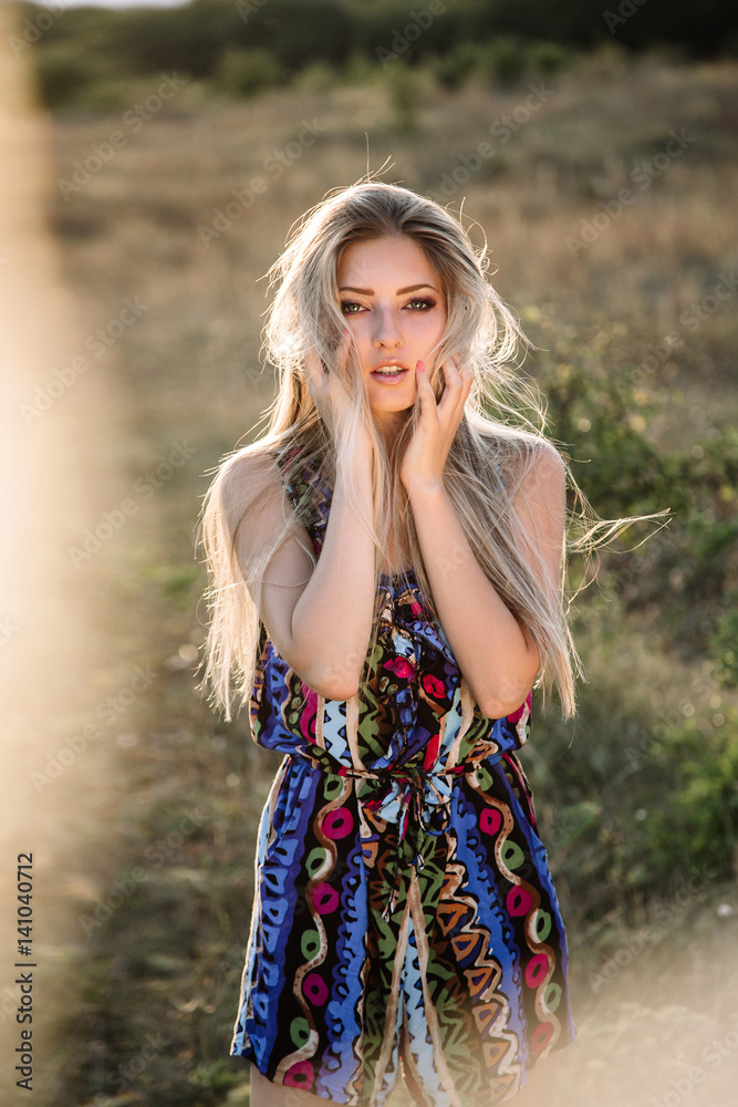 Naklejka premium beautiful dreamy blonde girl with blue eyes in a light turquoise dress lying on the stones