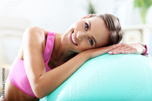 Smiling young woman with sports equipment at home.