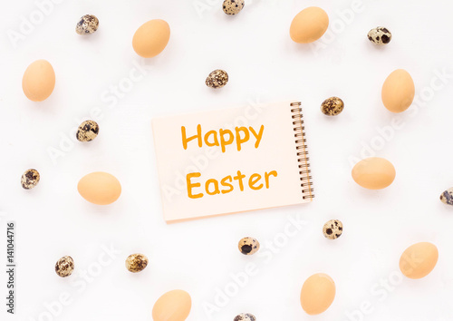 Happy Easter. Biege eggs, quail easter eggs and notebook on white background. Flat lay, top view