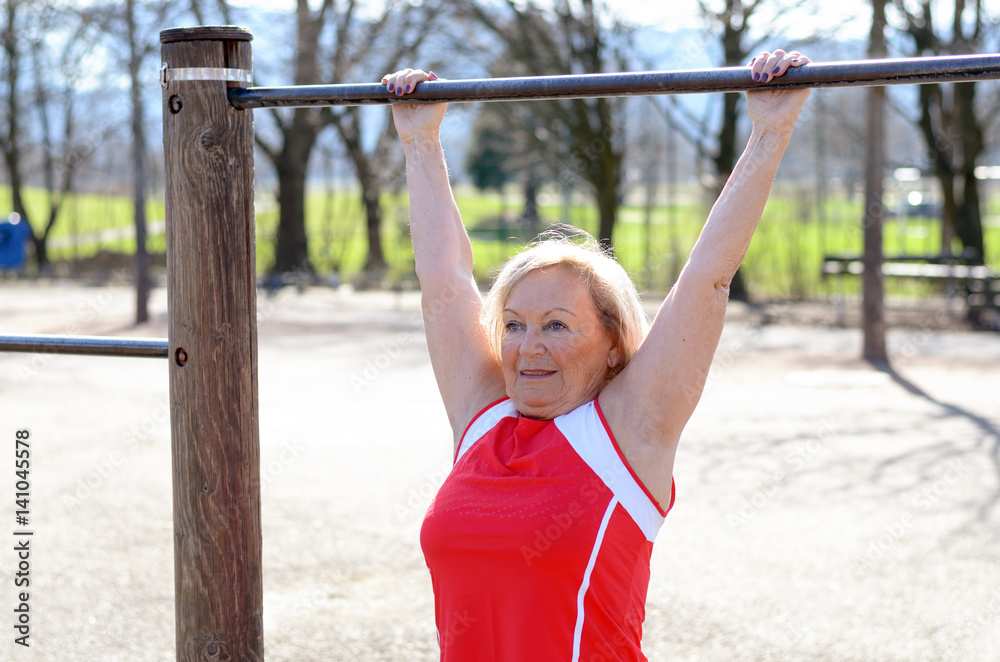 Happy senior woman working out on a bar