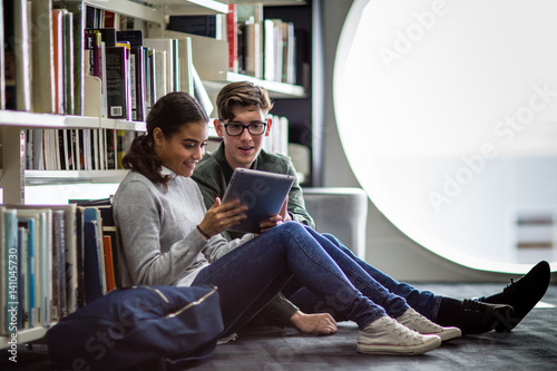 Students reading digital tablet in library photo