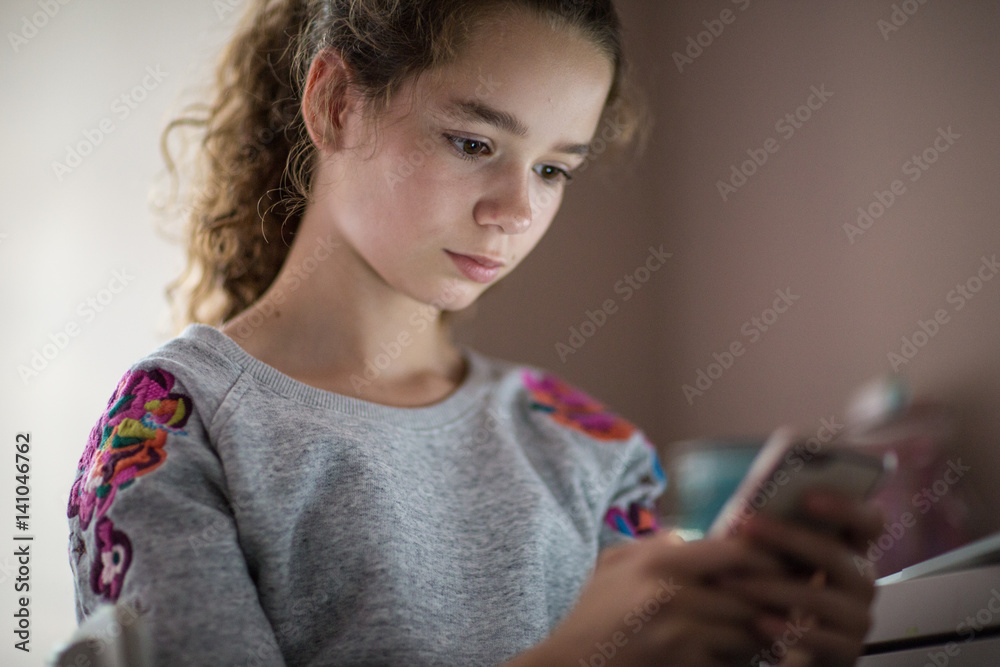 Teenager in bedroom looking at smartphone Teenager in bedroom looking at smartphone