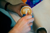 Man pours milk into latte coffee to create latte art pattern