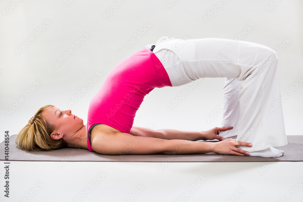 Fototapeta premium Woman exercising yoga indoor-Little Bridge Pose/Setuasana