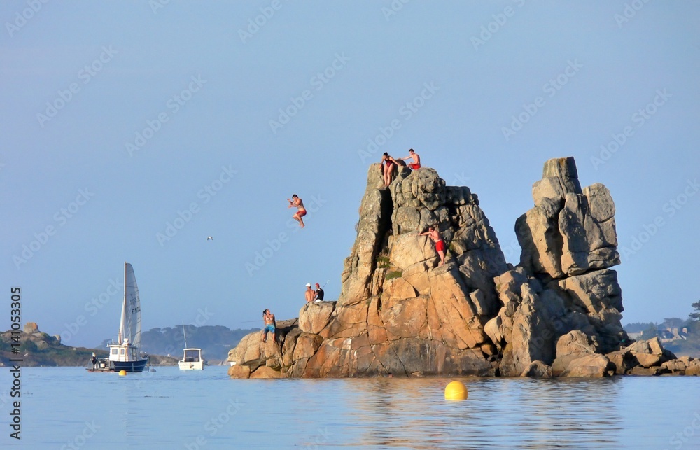 Des jeunes gens plongent depuis un gros rocher en Bretagne
