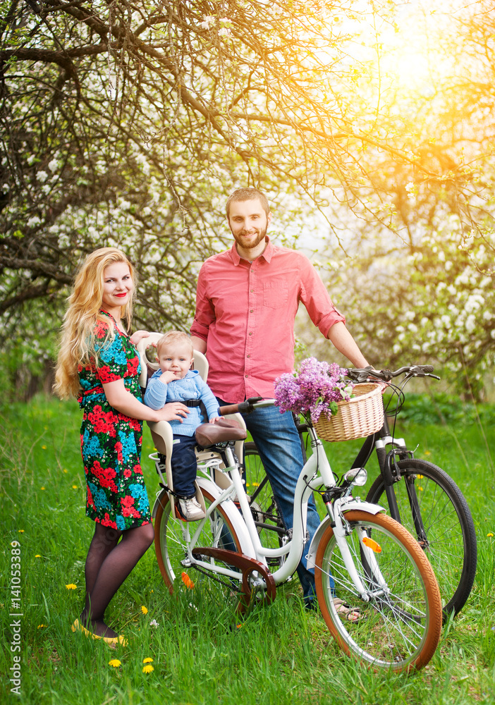 Young family on a bicycles in the spring garden Young family on a bicycles in the spring garden