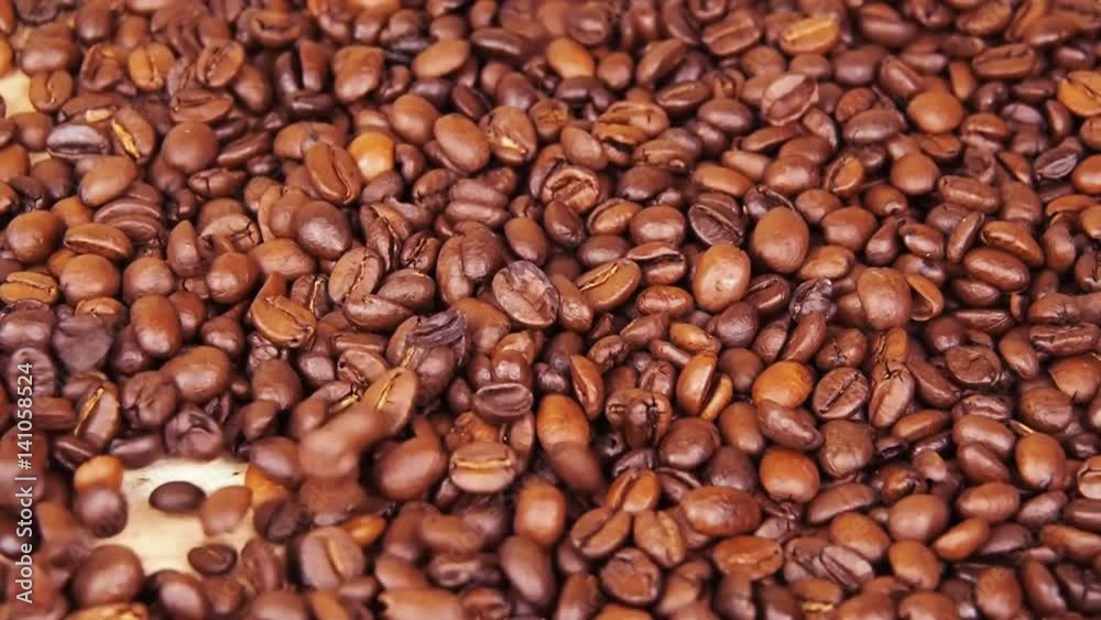 Grains of coffee close-up. Coffee fried grains are pouring down. Close-up.
