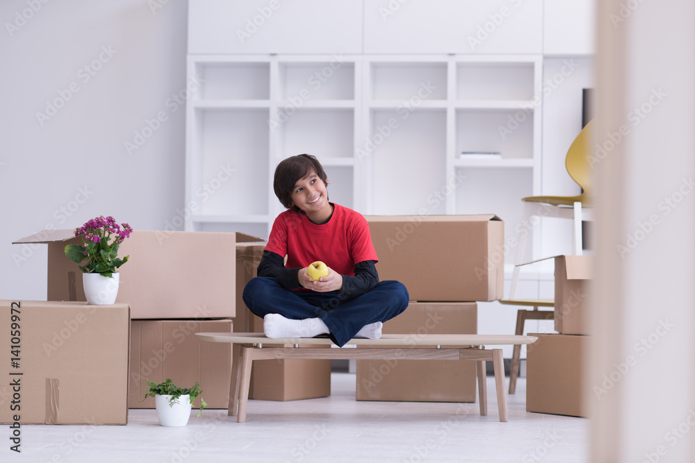 boy sitting on the table with cardboard boxes around him boy sitting on the table with cardboard boxes around him
