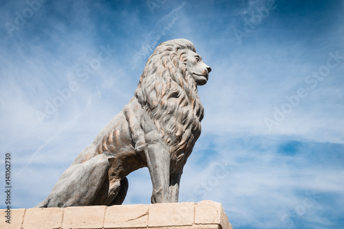 Bronze lion sculpture in blue sky