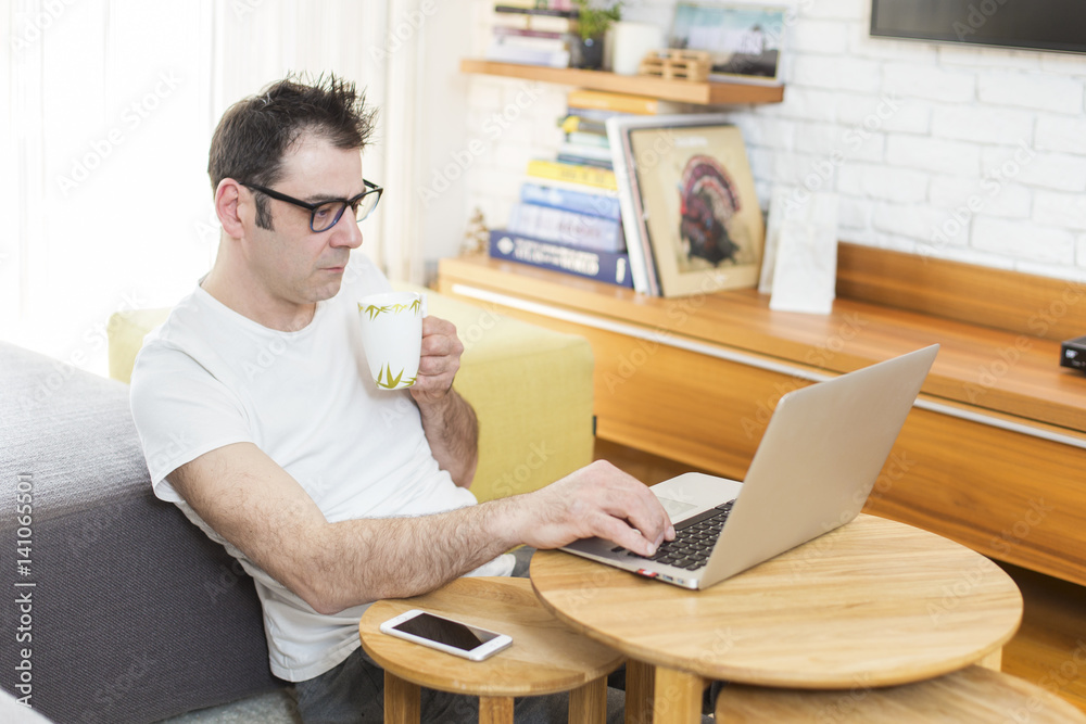 Man sitting in his living room and working on laptop.