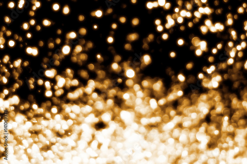 Golden abstract sparkles or glitter lights. Festive gold background. Defocused circles bokeh or particles. Template for design photo