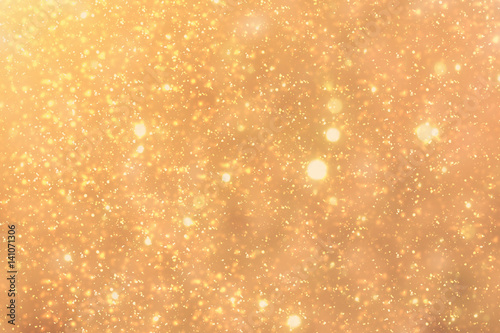 Golden rays and sparkles or glitter lights. Merry Christmas festive gold background.defocused circle bokeh or particles