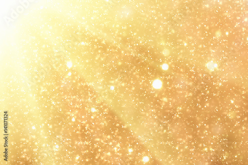 Golden rays and sparkles or glitter lights. Merry Christmas festive gold background.defocused circle bokeh or particles © Bokehstore