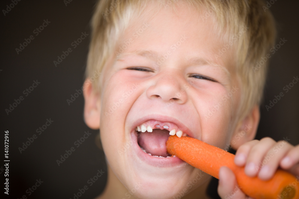 Portrait of cute toothless kid boy eating carrot. Happy child with vegetable. Healthy eating. Portrait of cute toothless kid boy eating carrot. Happy child with vegetable. Healthy eating.