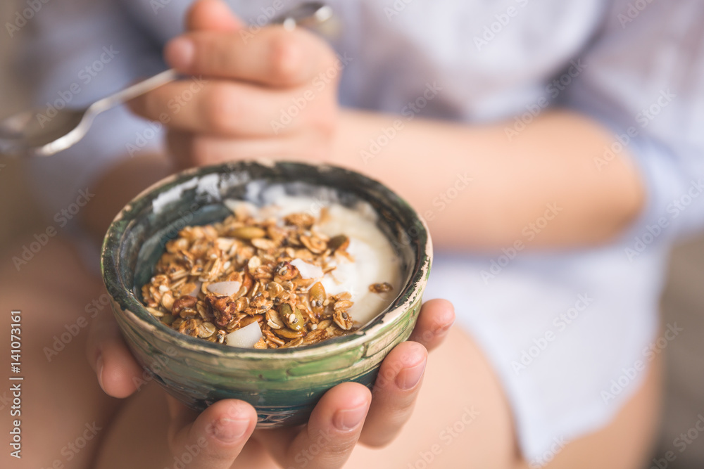 Young woman with muesli bowl. Girl eating breakfast cereals with nuts, pumpkin seeds, oats and yogurt in bowl. Girl holding homemade granola. Healthy snack or breakfast in the morning. Young woman with muesli bowl. Girl eating breakfast cereals with nuts, pumpkin seeds, oats and yogurt in bowl. Girl holding homemade granola. Healthy snack or breakfast in the morning.