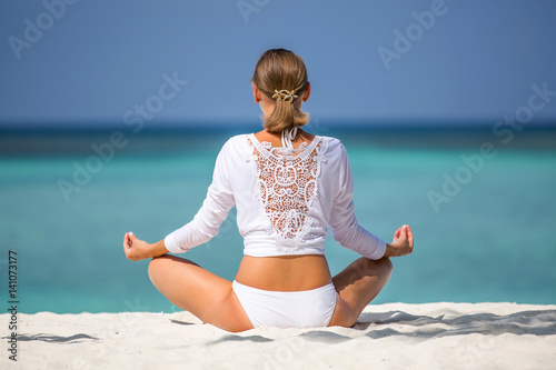 Meditation. Photo of a woman who is sitting in the lotus position on the ocean coast. Maldives