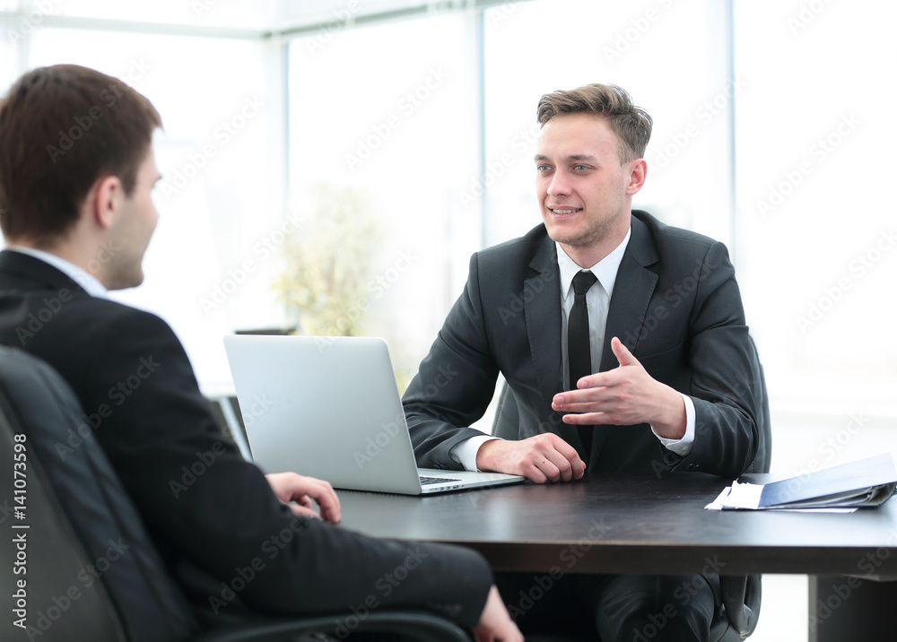 Manager sits behind the Desk and talks to the client