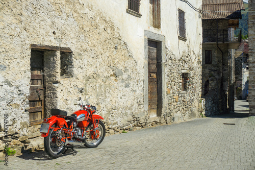 Red bike parked on the street of old town in Italy