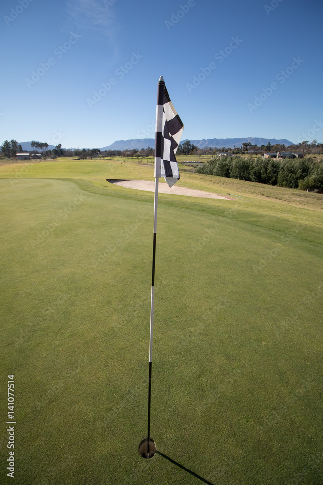 Obraz premium Wide angle view of a flag in the hole on the green of a golf course