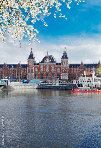 cityscape with central railway station and old town canal in Amsterdam at spring, Holland