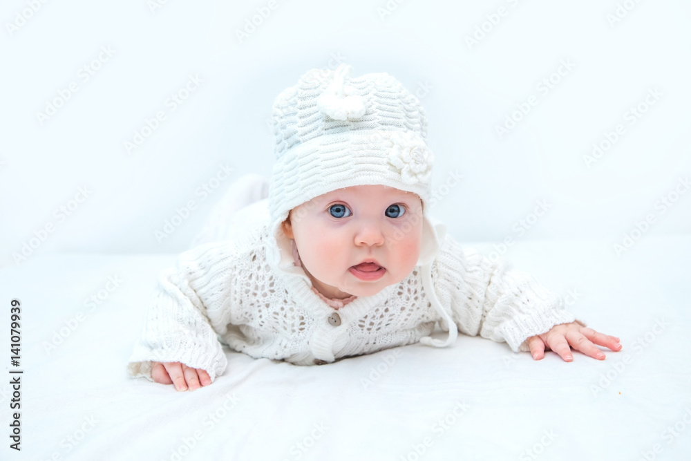 The baby is dressed in white and on a white background lifted on his hands. The baby is dressed in white and on a white background lifted on his hands.