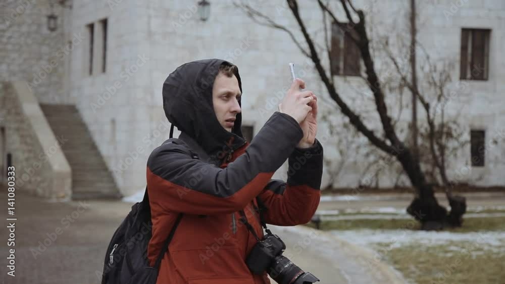 Portrait of happy young man tourists in hood with smartphone in the city Portrait of happy young man tourists in hood with smartphone in the city